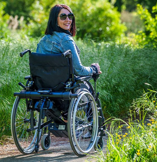 Femme qui se balade dans un parc en fauteuil Benoit systemes 
