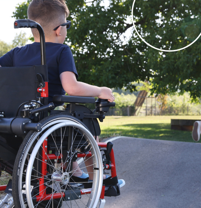 Un jeune garçon sur un fauteuil roulant avec une motorisation Minotor de Benoit Systemes. 