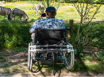 Homme photographiant un paysage en fauteuil roulant avec une double motorisation Maxi Minotor 2.1 de Benoit Systemes.